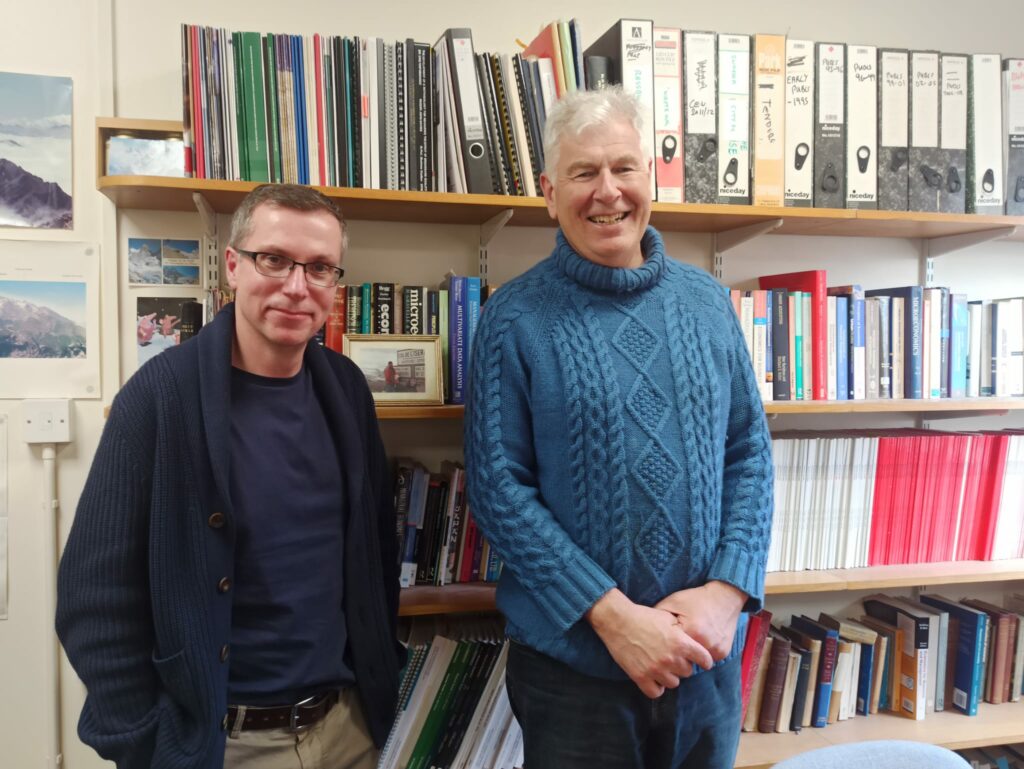 Max Munday et Mark Lang devant la bibliothèque de leur bureau à l'Université de Cardiff.